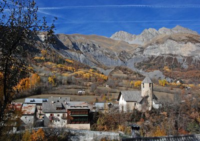 Entraunes en automne. L'église, sa toiture en bardeaux de mélèzes et son clocher à couverture dissymétrique. Paysages de bocages