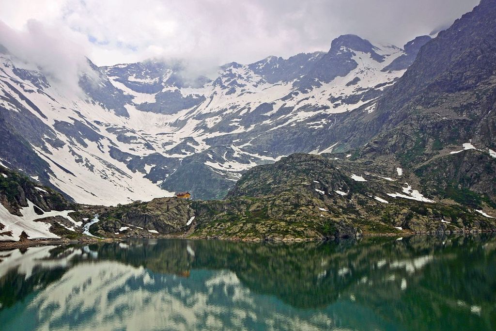 Randonnée Argentera. Le lac Chiotas en début d'été, nombreux névés en arrière plan, temps nuageux.